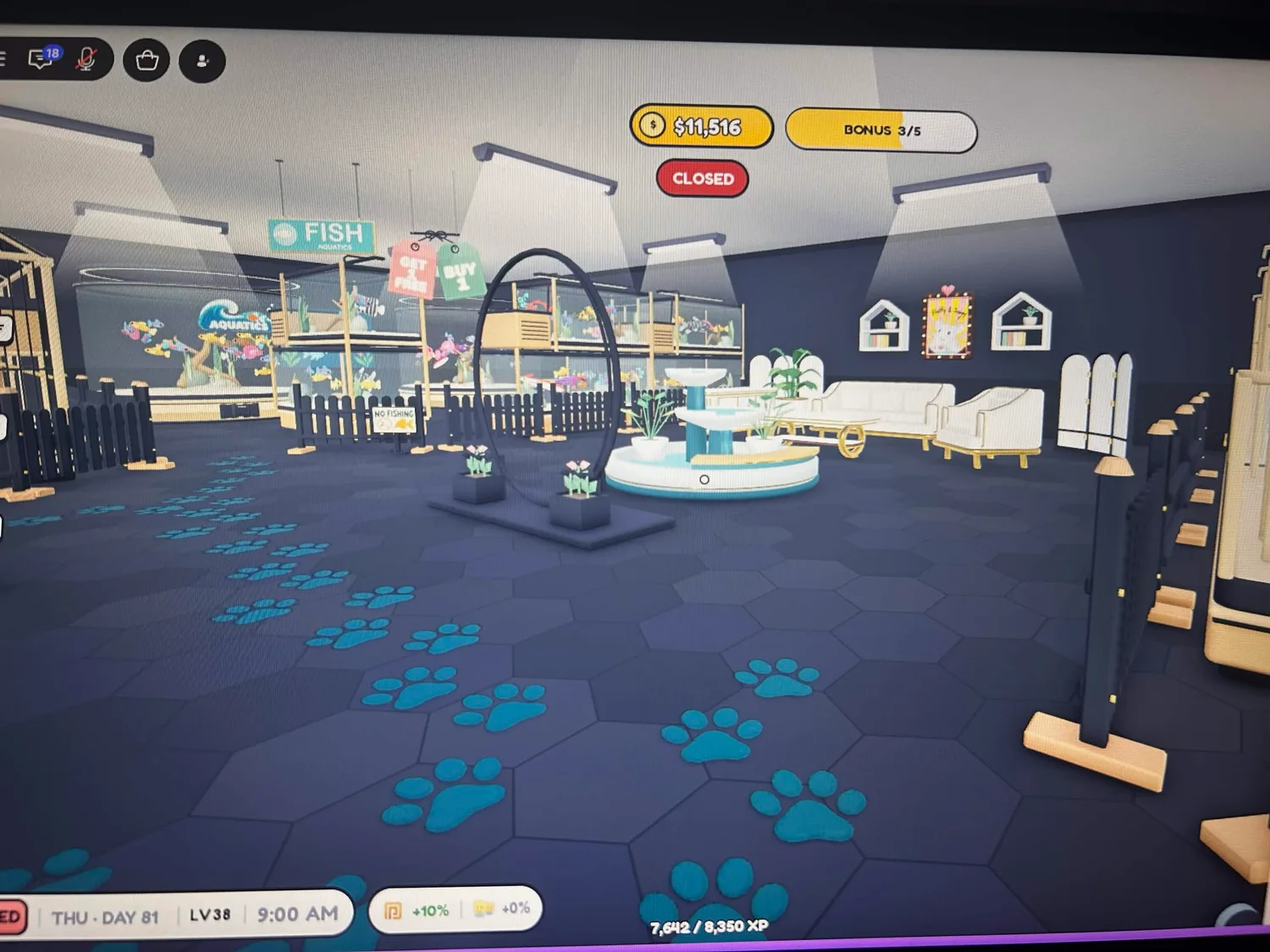 An open area beside the fish tanks with a fountain, white seating and teal paw-print accents.
